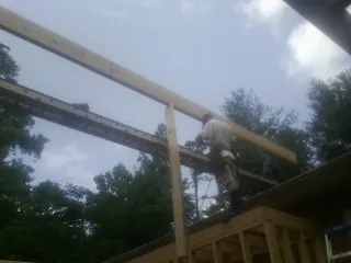 Carpenter setting a ridge beam over a new addition frame — Ice Dam Removal by Roofing Brothers in Lake Pleasant