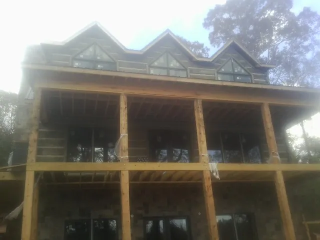 Dormers and porch framing on a large log home under construction — Roof Coating work by our crew in Lake Pleasant