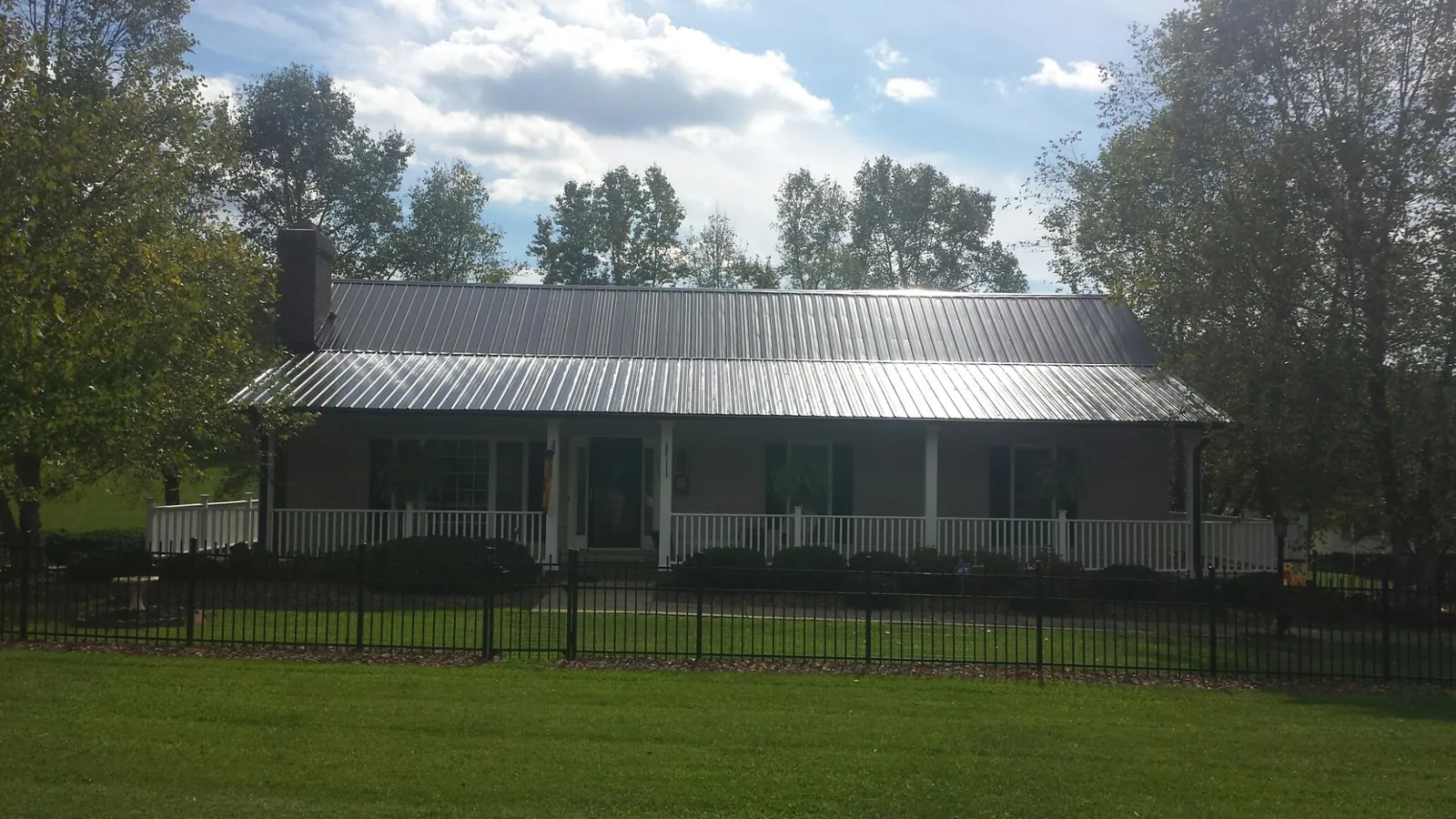 Gray metal roof on a brick ranch with a full width front porch — Gutter Guard Installation work by our crew in Lake Pleasant