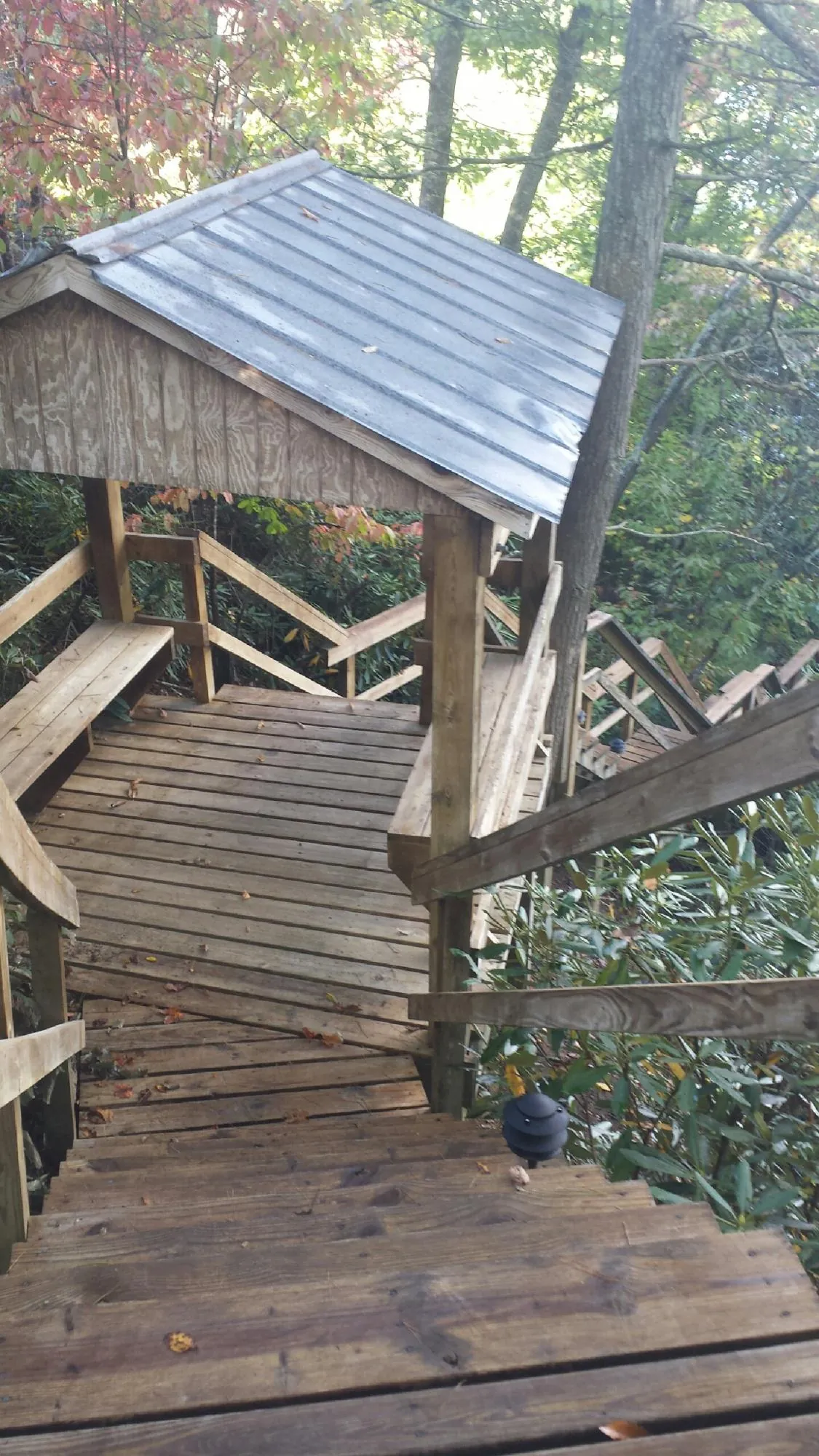 Metal roofed shelter over wooden steps on a wooded walkway — Skylight Repair & Installation work by our crew in Lake Pleasant