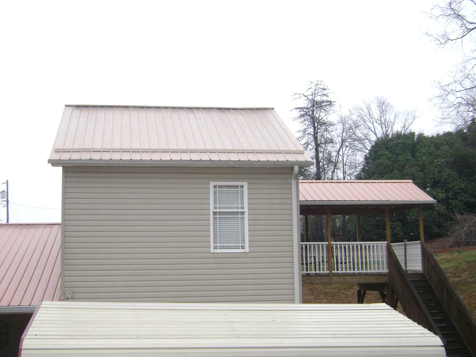 Tan metal roofs on a two story addition and attached porch, from a Roof Replacement job in Lake Pleasant