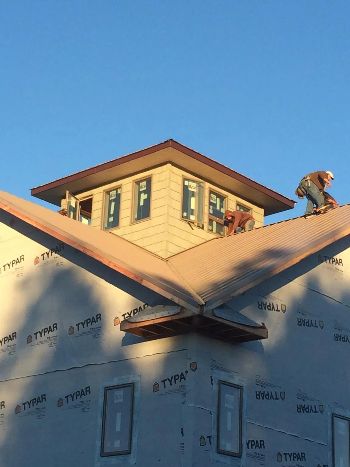 Roofers working around a rooftop cupola on a new metal roof at sunset — Roof Waterproofing in Lake Pleasant by Roofing Brothers
